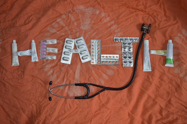 Tablet strips and ointment tubes laid out on a table to read “health” with a stethescope in the middle.